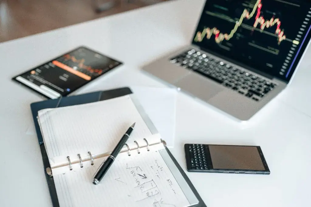 Desk with laptop charts, tablet, notebook and pen used for risk analysis